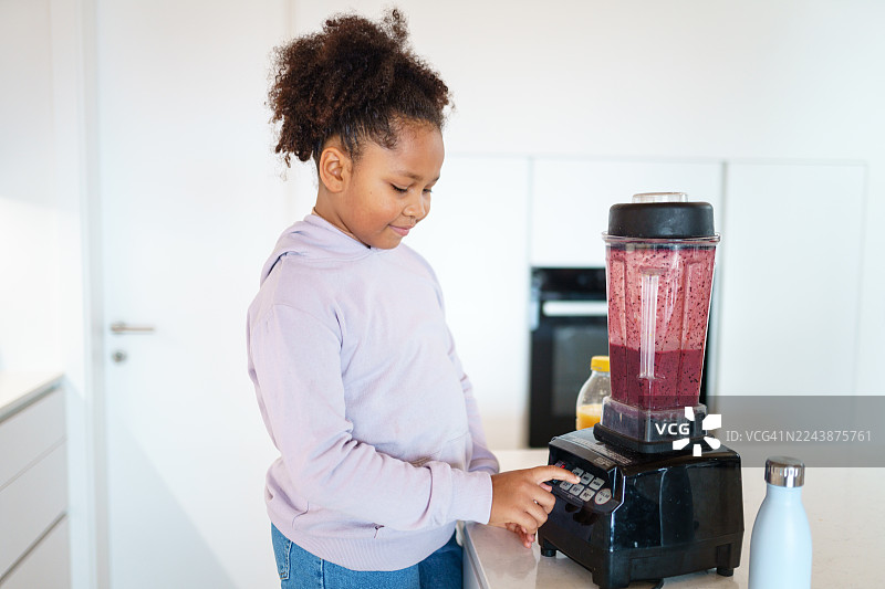 混血小女孩在现代厨房里制作冰沙图片素材