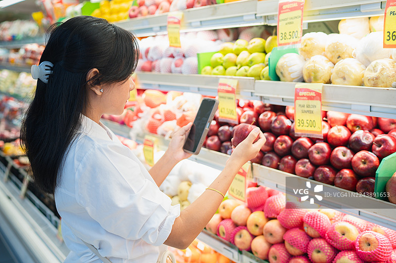一位女士在购买水果时查看价格标签图片素材