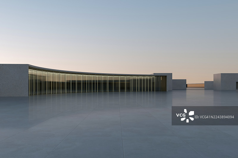 玻璃幕墙的混凝土建筑与黄昏天空，现代建筑前方的空旷广场图片素材