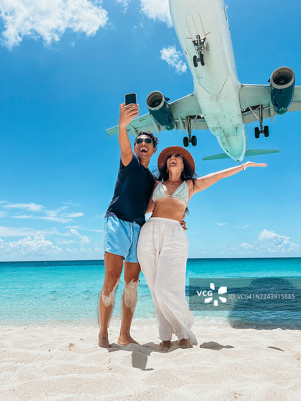 情侣在海滩上自拍，飞机背景图片素材