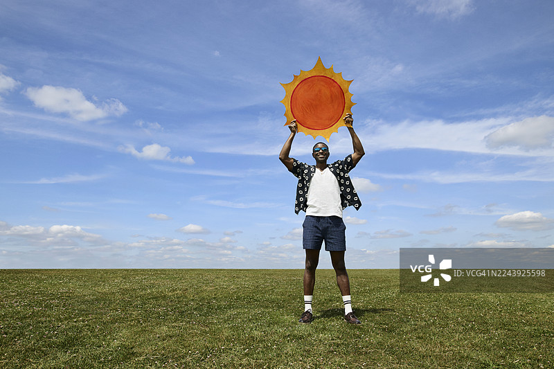 一位面带微笑的男士手持太阳形状的剪纸图片素材