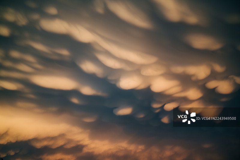 壮丽的乳状云特写布满天空，在日落或日出时被鲜艳的红色、橙色和深灰色照亮。图片素材