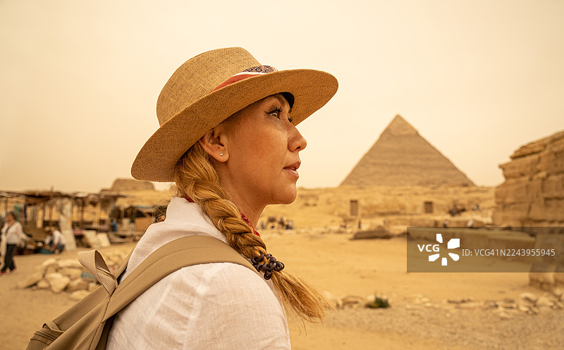 一位女性游客在度假，站在埃及吉萨大金字塔前。开罗 - 吉萨图片素材