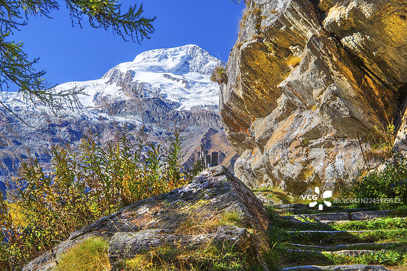 秋季，瑞士瓦莱州萨斯费萨斯山谷历史教堂步道，远眺阿尔卑尔峰（4206米）图片素材