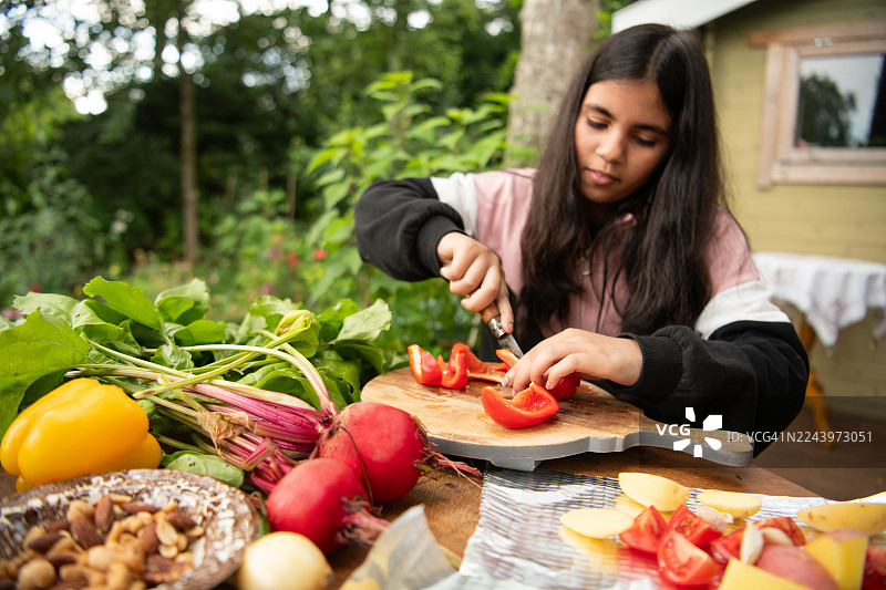 一个女孩正在准备新鲜蔬菜，准备将它们放入烤箱图片素材