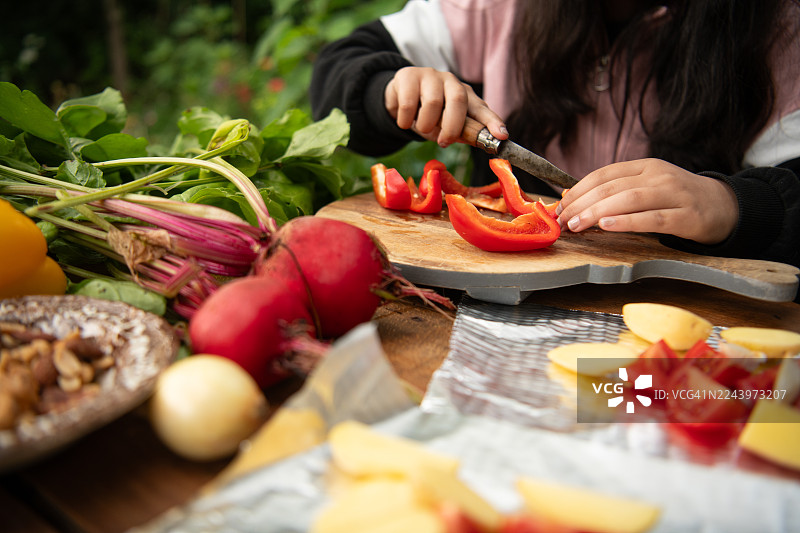 一位女孩正在准备新鲜蔬菜，准备送入烤箱图片素材