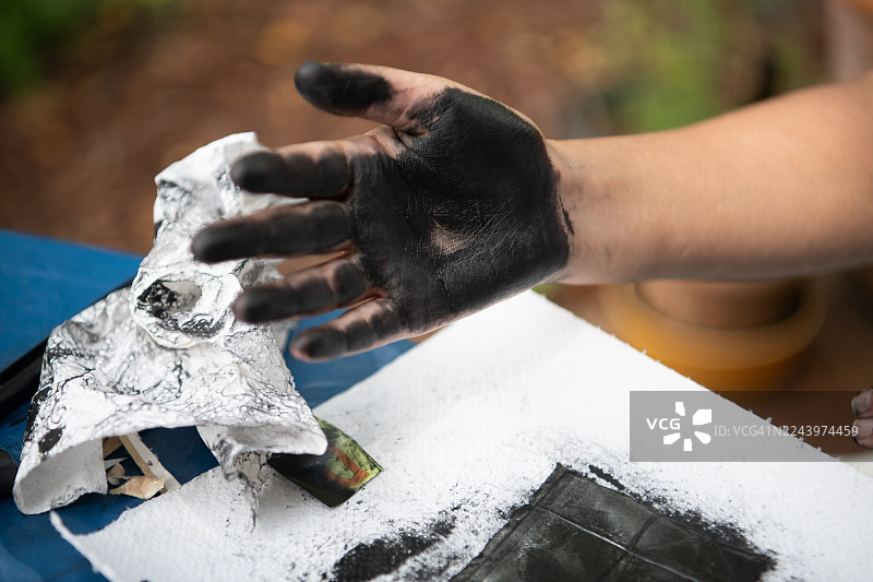 女孩沾满墨水的手近景，她用果汁盒制作单版画：利用果汁盒内部制作单版画图片素材