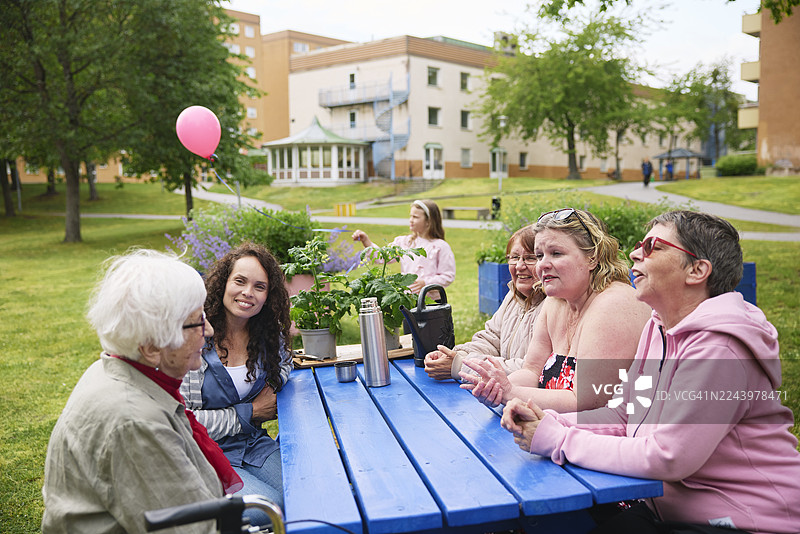 几位女士在公园长椅上坐着，边聊天边享受休闲时光图片素材
