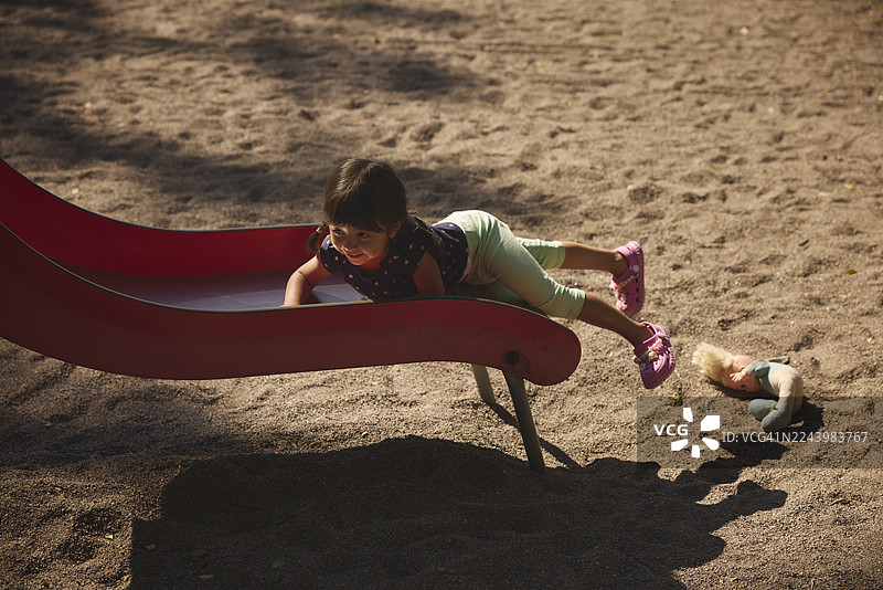 快乐的女孩在游乐场的滑梯上玩耍图片素材