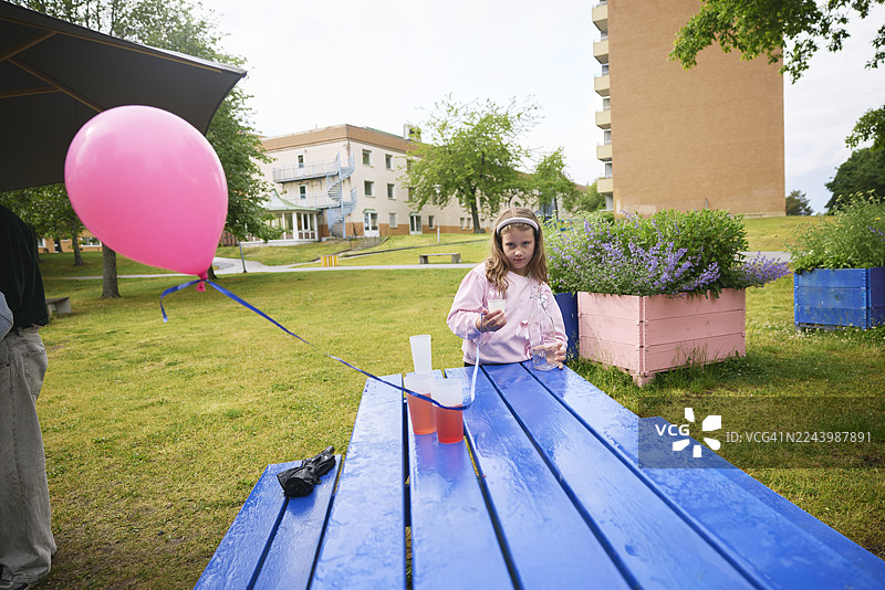 女孩在公园里拿着一杯水和气球的肖像图片素材