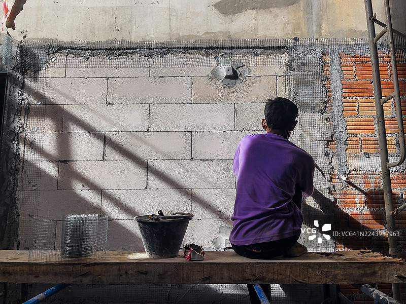 建筑工人正在内砌块墙上粘贴网格图片素材