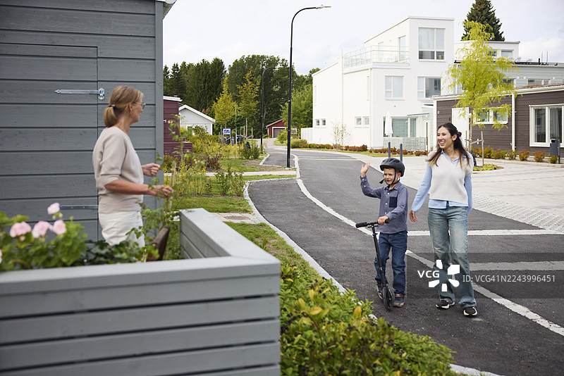 母子俩在住宅区散步时向邻居打招呼图片素材