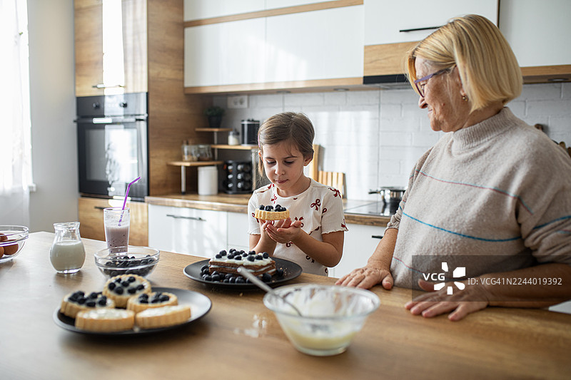 祖母和孩子一起享用自制蓝莓甜点的快乐家庭时光图片素材