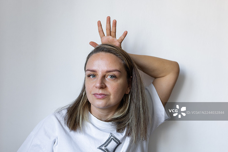 自信的女性在休闲工作室肖像照中，手放在脑后摆姿势图片素材