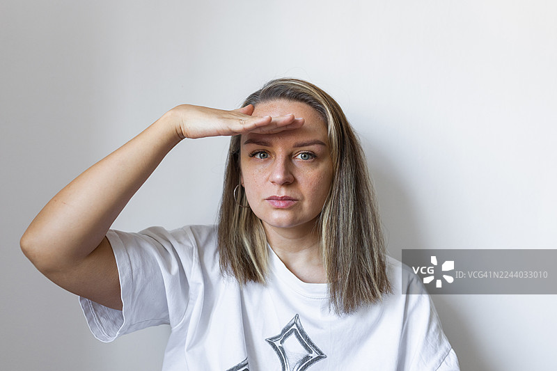 一名女子在纯白色背景前用手遮挡眼睛的肖像照图片素材