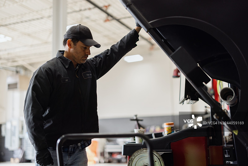 汽车维修技师在汽车修理厂检查汽车诊断仪图片素材