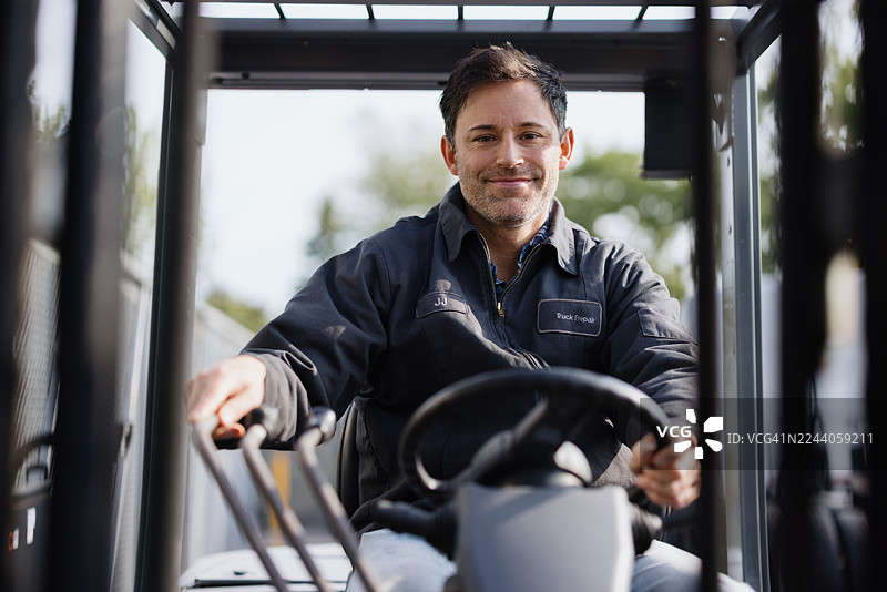 仓库工人驾驶叉车并对镜头微笑图片素材