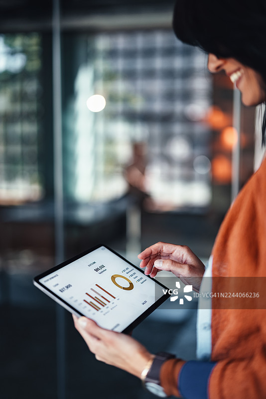 专业人士在现代办公室环境中使用带有金融图表的平板电脑图片素材