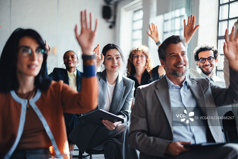 多元化团队在办公室会议中举手，展现投入和协作图片素材