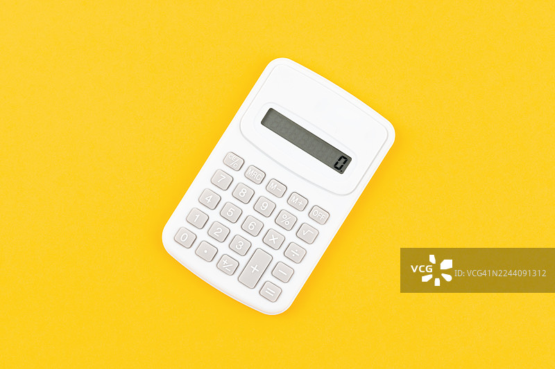 黄色背景上的白色财务计算器，留有复制空间的构图。图片素材