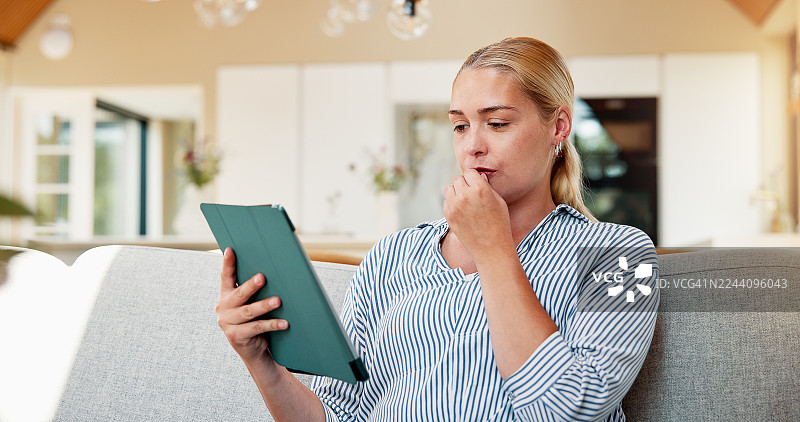 女性在家远程办公，手持平板电脑思考，进行研究、校对和更新草稿。这位自由职业者正在阅读文章、审阅编辑反馈并准备提交出版。图片素材