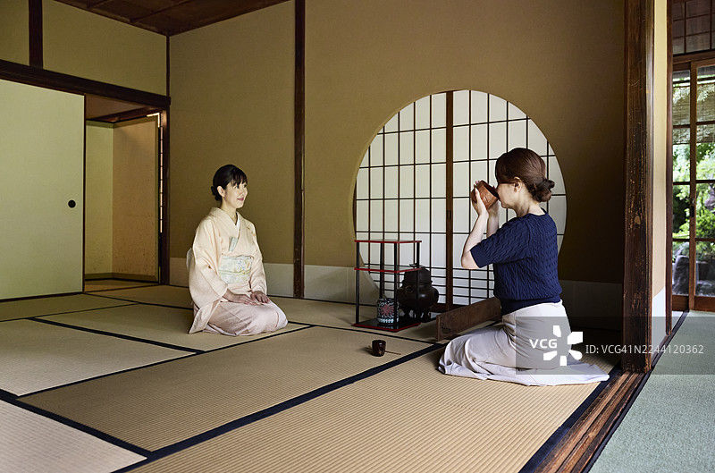 女士品尝传统茶，女主人在旁图片素材