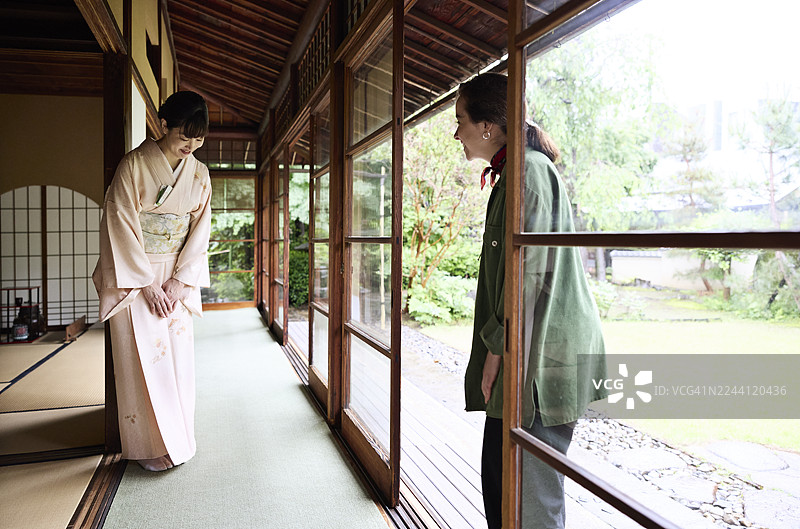 一位女服务员正对着一位年轻女子鞠躬图片素材