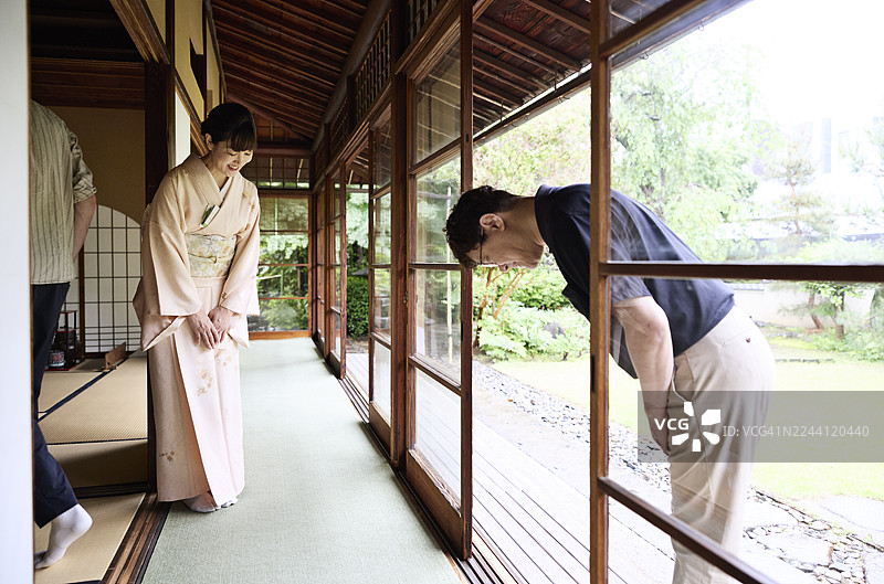 一位成熟的女主人在门口迎接一位男士图片素材