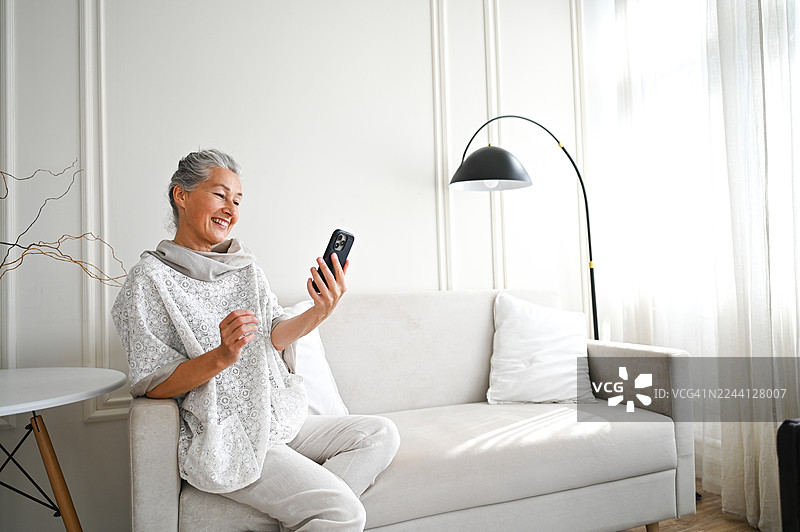 一位成熟的成年女性在家中通过智能手机享受视频通话图片素材