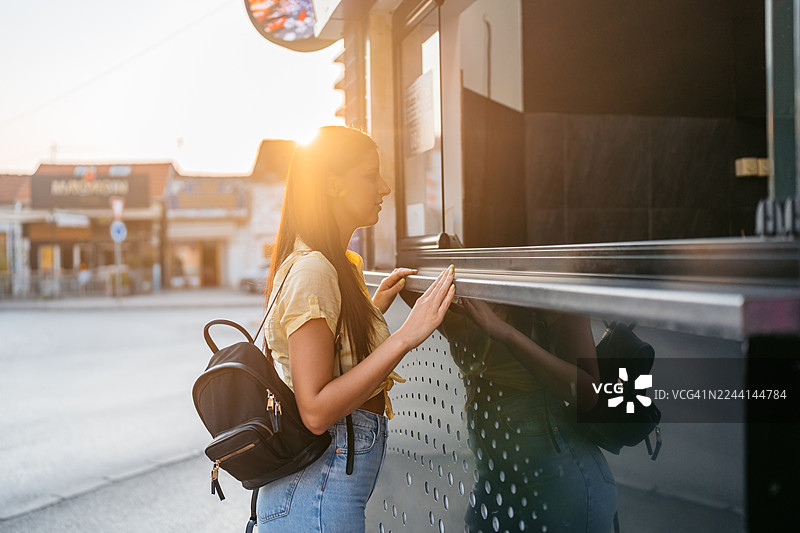年轻女子在快餐街边售货亭外点三明治图片素材
