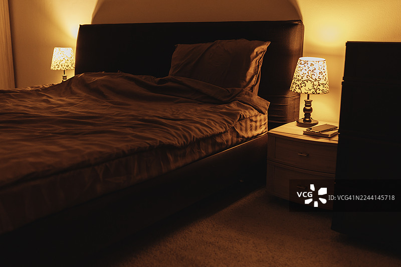 夜间舒适的酒店卧室，暖色灯光和柔软的床上用品营造出宁静的氛围图片素材