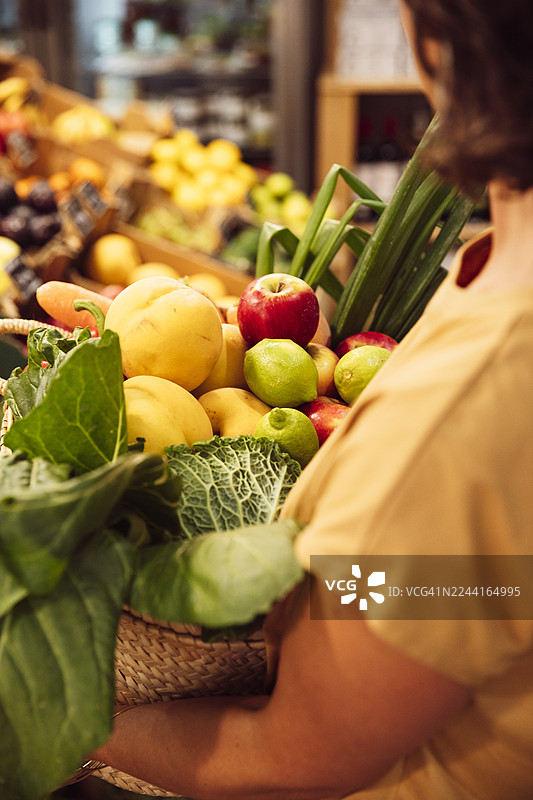 一位女士在有机超市用草篮购买蔬菜图片素材