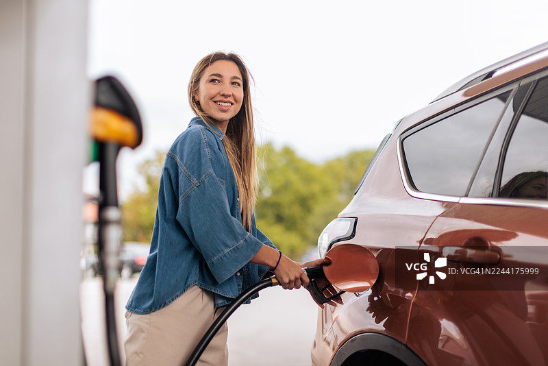 微笑的女士在加油站给汽车加油图片素材