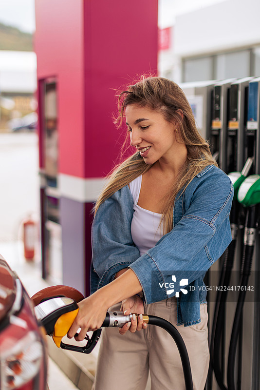 面带微笑的女士在加油站为汽车加油图片素材