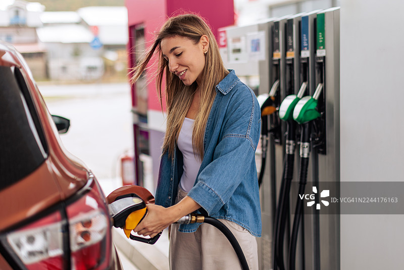 面带微笑的女士在加油站给汽车加油图片素材