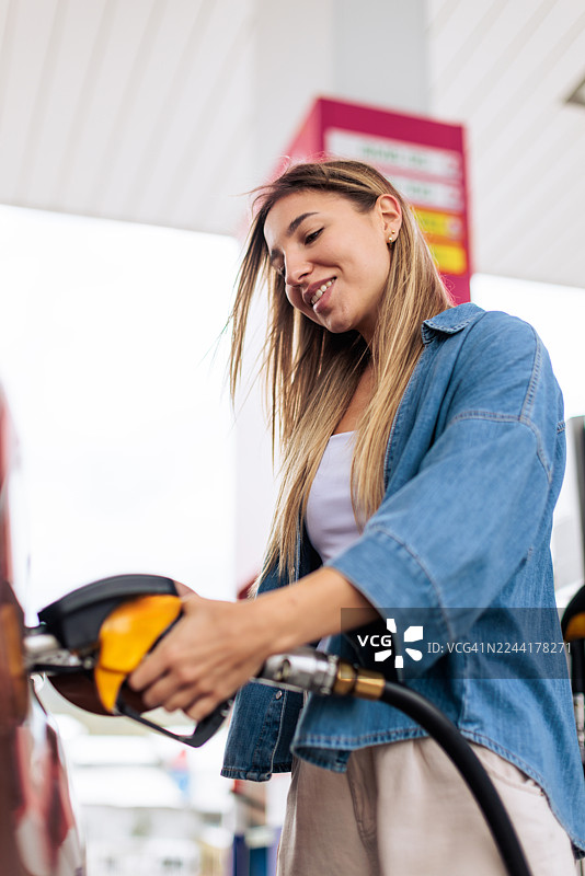 面带微笑的女士在加油站给汽车加油图片素材