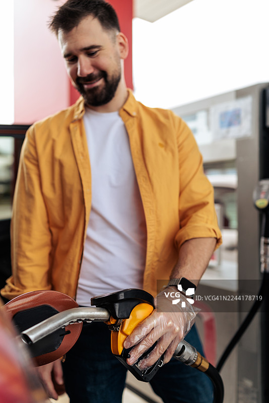 面带微笑的男士在加油站给汽车加油图片素材