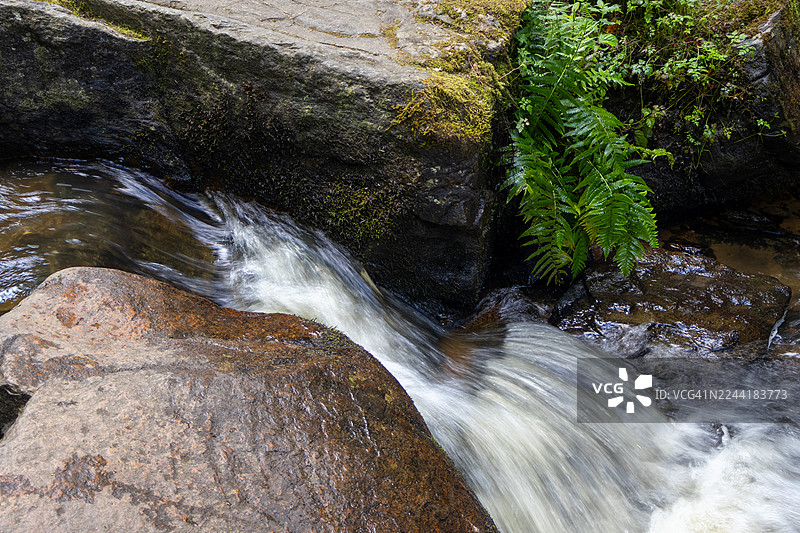 岩石与绿色植被间奔腾瀑布的俯视视角图片素材