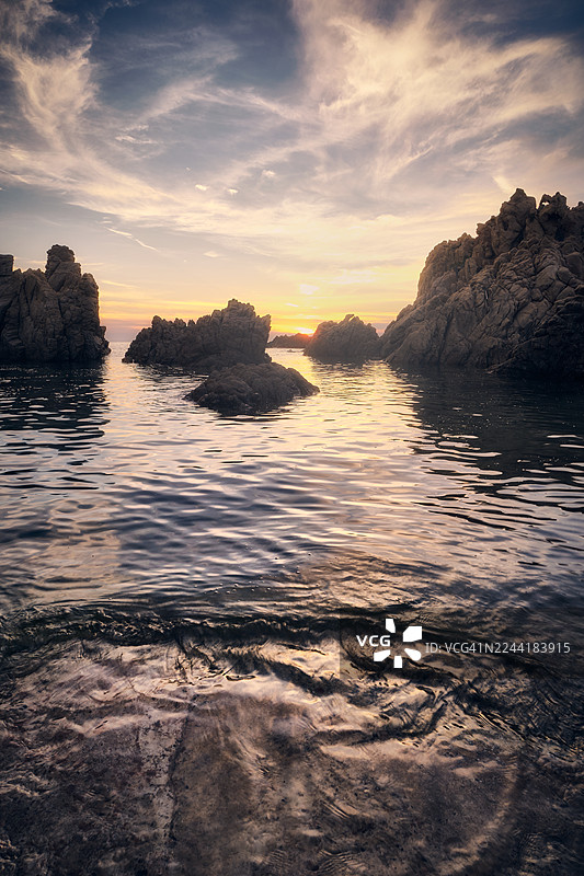 意大利，利科西，岩石海岸上壮丽的日落，平静的海水映照着天空温暖的色调图片素材