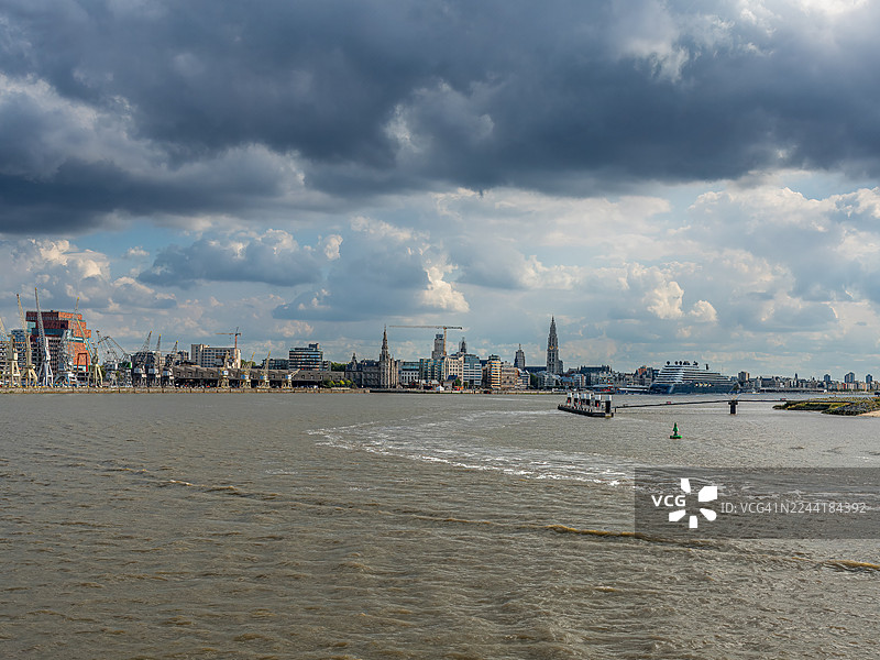 比利时安特卫普，河畔城市天际线风景，戏剧性的多云天空下，拥有历史建筑和港口基础设施图片素材