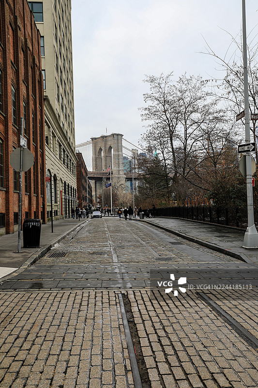 阴天，鹅卵石街道通往纽约市 Dumbo 区的布鲁克林大桥，纽约，美国，USA图片素材