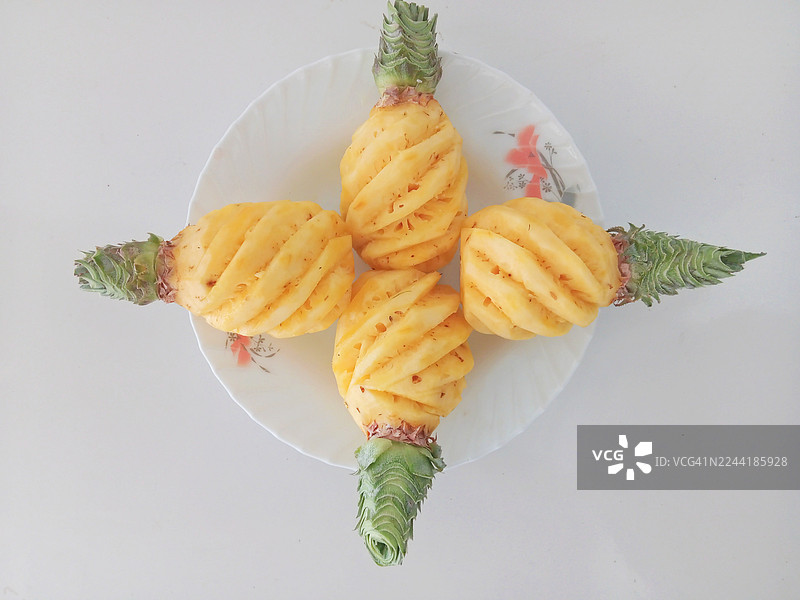俯视角度拍摄的，新鲜的去皮菠萝摆放在白色盘子上，准备食用图片素材
