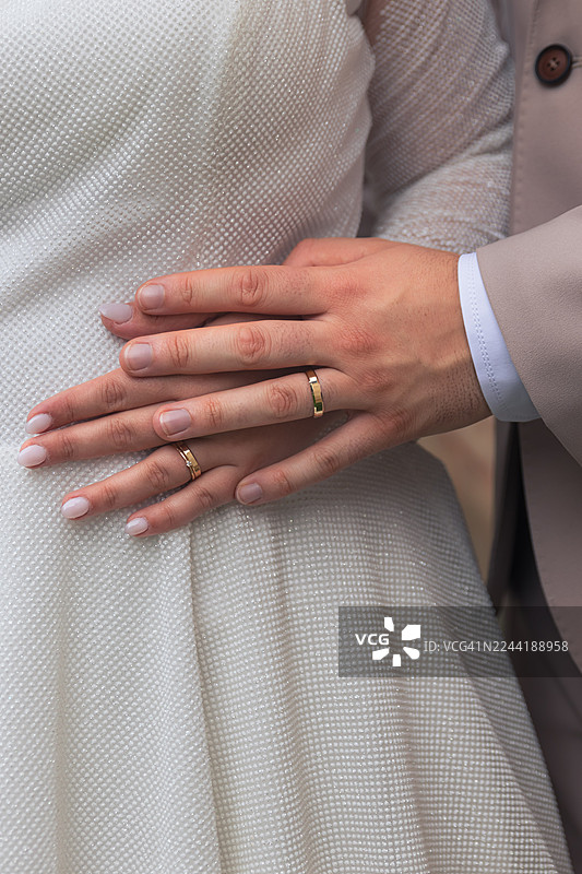 特写一对情侣戴着婚戒的手，象征着承诺与结合图片素材