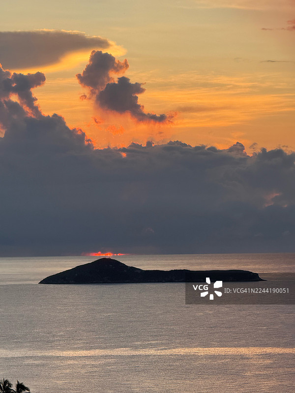 巴拿马里奥哈托，戏剧性的日落映照在宁静的海面上，远方地平线上是一座岛屿的剪影，构成一幅宁静如画的风景图片素材