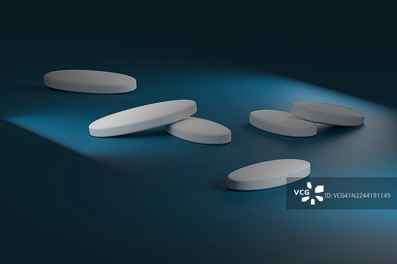 白色椭圆形药丸在蓝色表面上的极简工作室照片，带有戏剧性的灯光图片素材