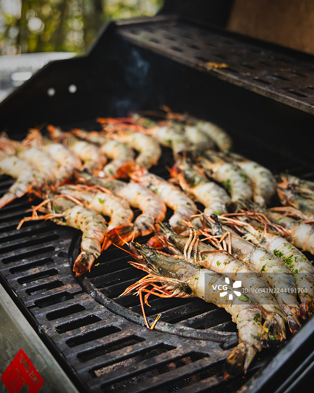 鲜美的虾在炙热的烤架上烹饪，是夏日大餐或户外聚会的完美选择图片素材