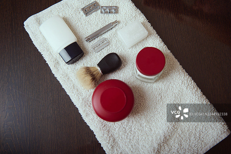 毛巾上的梳妆套装，包含化妆刷、剃须刀、刀片和红色唇膏罐图片素材