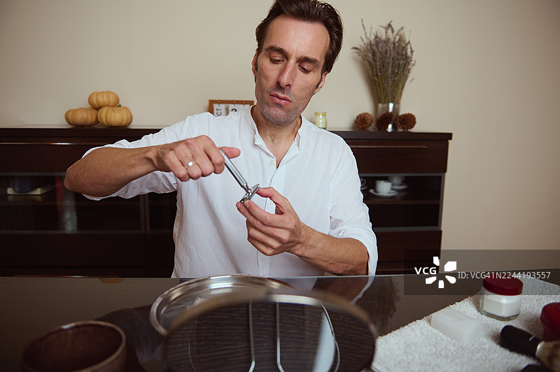 男人在厨房柜台使用胡桃夹子，背景是秋季装饰和宁静的居家时光图片素材