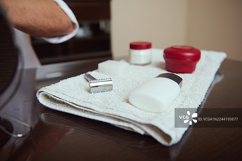 浴室里，剃须刀、香皂和剃须膏放在白色毛巾上，组成一套剃须用品。图片素材