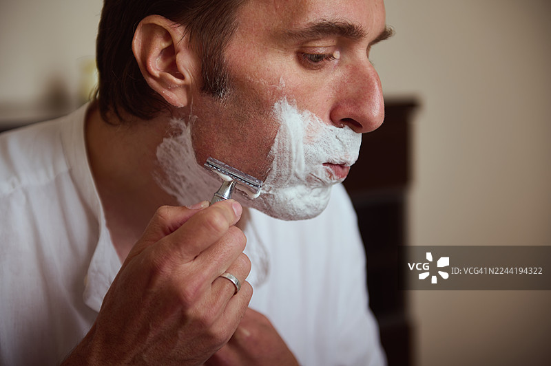 特写镜头下，男人早上刮胡子，脸上涂满剃须泡沫的梳理瞬间图片素材